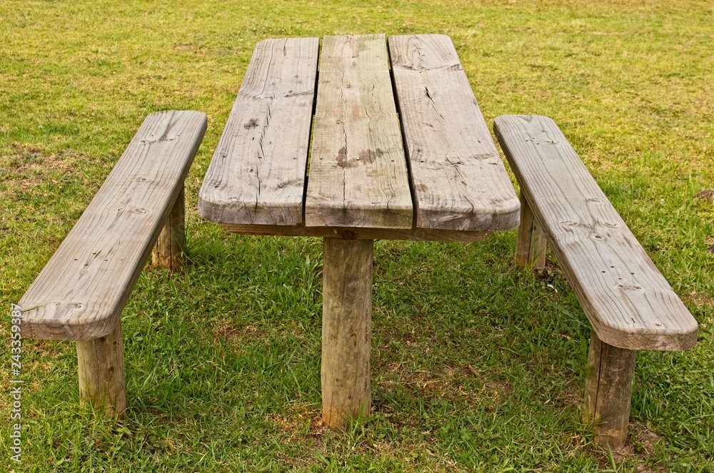 A wooden park bench. Outdoor eating or picnic concept image. A wooden park bench. Outdoor eating or picnic concept image.