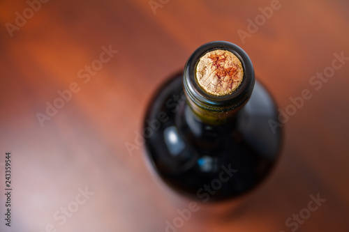 Dark red wine bottle on a dark wood table with the cork in focus 