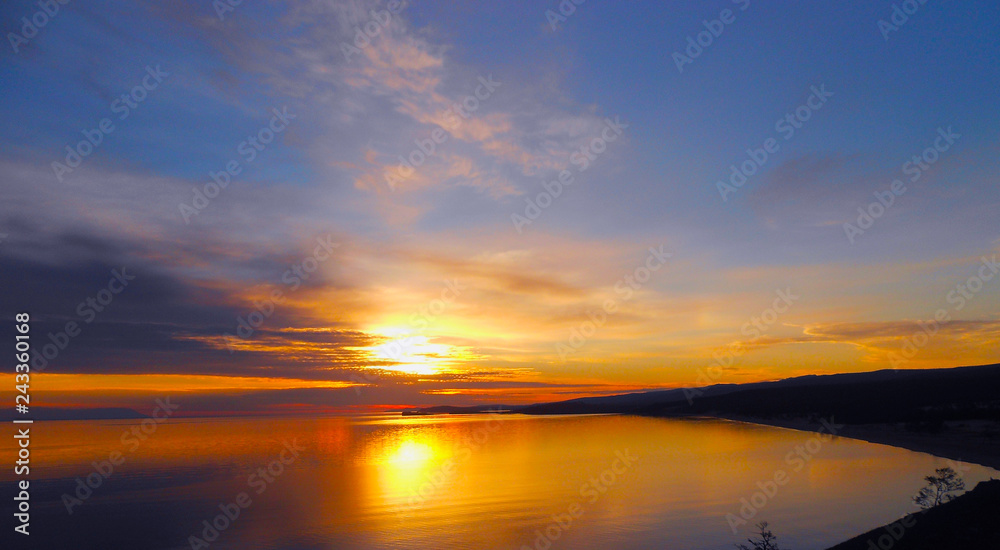 Bay in golden shades at sunset. Bright sunrise landscape in sea. Flaming colors of early morning. Dawn silence on lake.