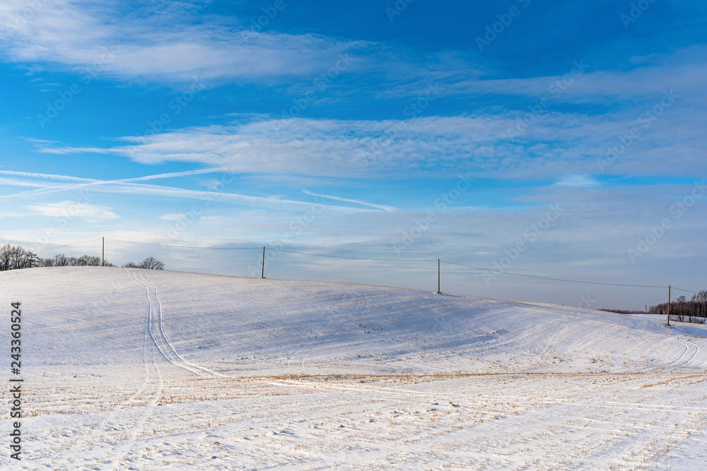 Empty Countryside Landscape in Sunny Winter Day with Snow Covering the Ground with Power Lines in Frame, Abstract Background with Deep Look