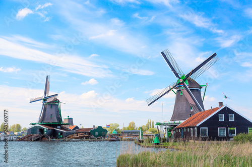 Dutch typical landscape. Traditional old dutch windmills against blue cloudy sky in the Zaanse Schans village, Netherlands. Famous tourism place. © Nikolay N. Antonov