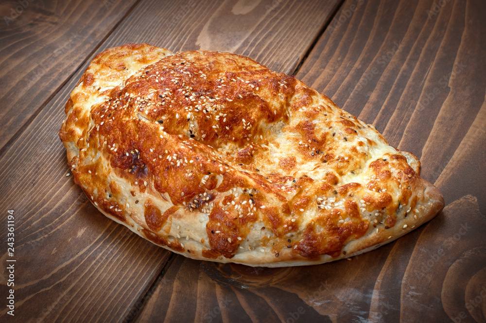 Italian pirogue pizza on wooden table with melting baked cheese Italian pirogue pizza on wooden table with melting baked cheese