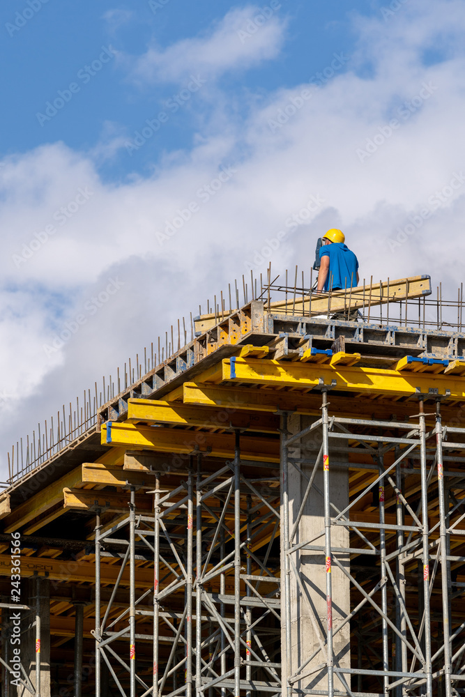 Fototapeta premium Man in protect wear looking through surveyor on building element