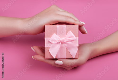 Fototapeta Naklejka Na Ścianę i Meble -  top view hand woman holding pink gift box for valentines day on pink pastel color background