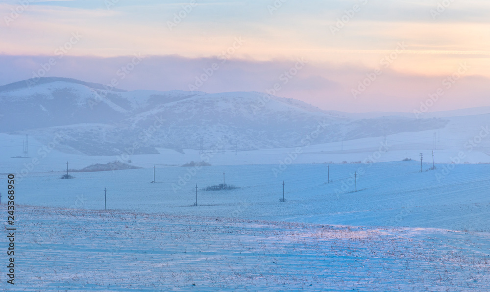 Sunset over hills covered with snow