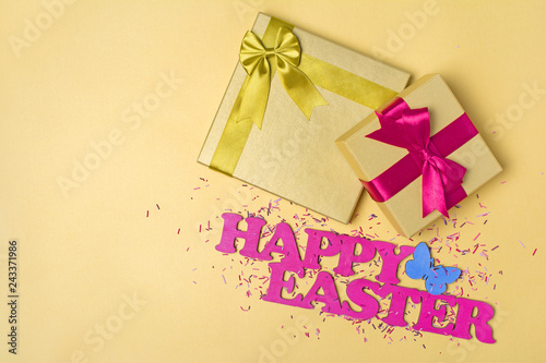 Pink text of happy easter and golden gift boxes with satin bows and sugar sprinkles