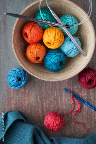 Top view of various yarn balls and latch hook on textured background
