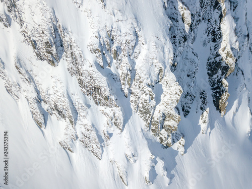 Aerial view of snow covered terrain in mountain area. Mountains in central Switzerland. Alps with snow in beautiful light with shadow and sun.