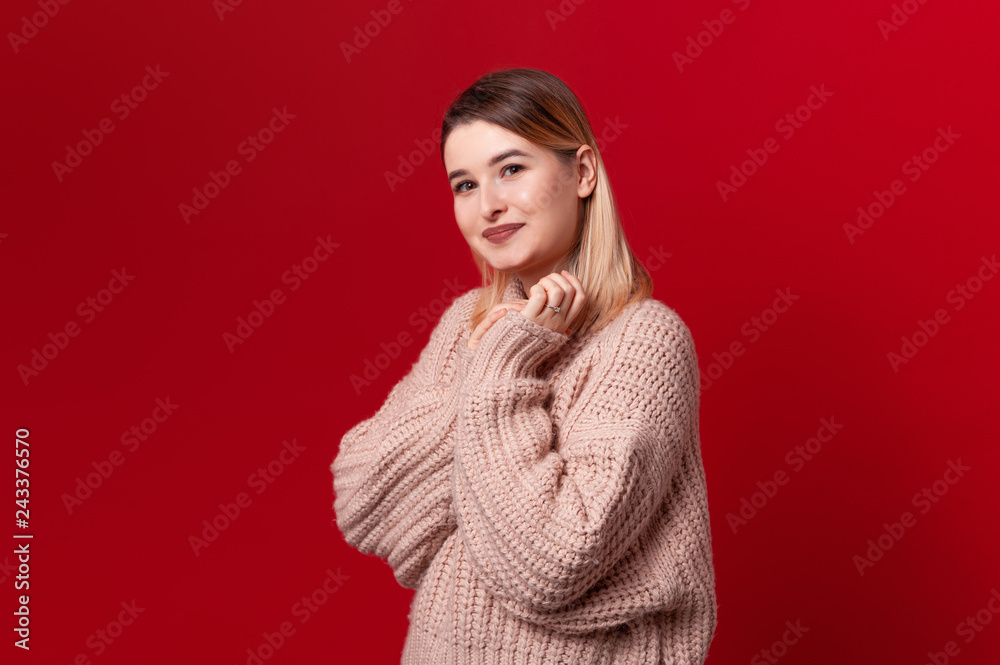 Portrait of  beautiful  woman in love, holding clasped hands over chest, over red background