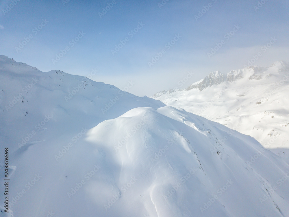 Aerial view of snow covered mountains in Swiss alps. Beautiful panorama of wild and tranquil backcountry in alpine area.