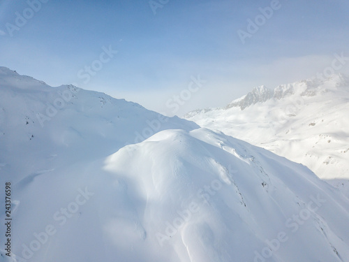 Aerial view of snow covered mountains in Swiss alps. Beautiful panorama of wild and tranquil backcountry in alpine area. © Mario