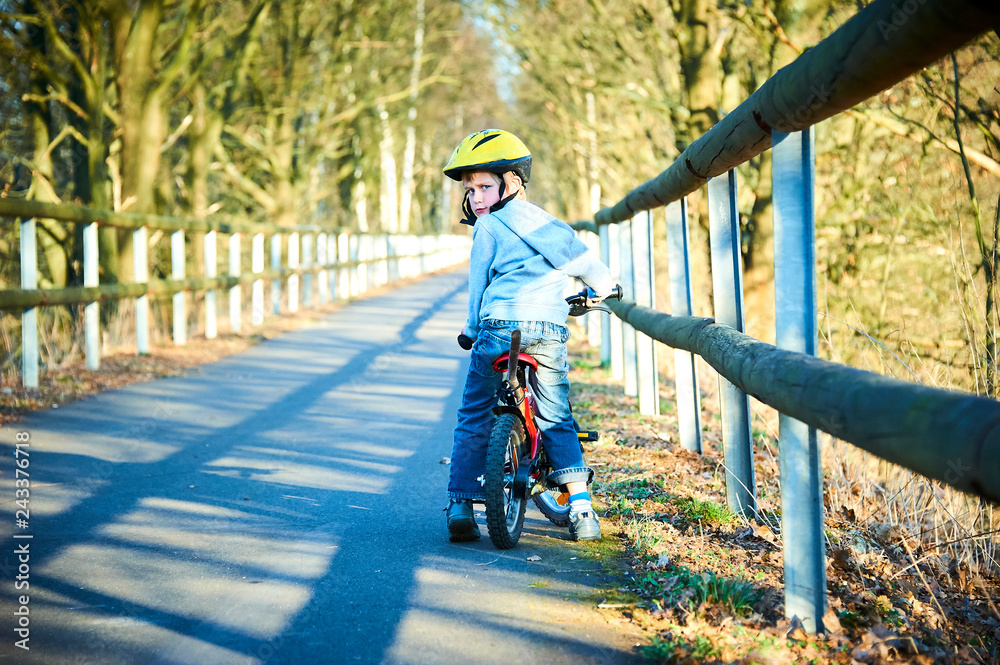 Obraz premium Boy riding his bike on a spring country track. Road concept for safety and child development