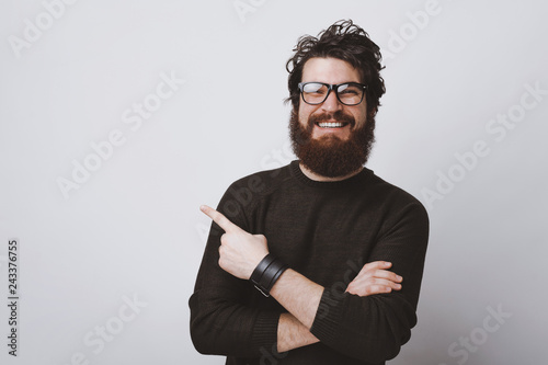 Stylish hipster model in glasses is pointing at  copy  space with crossed hands