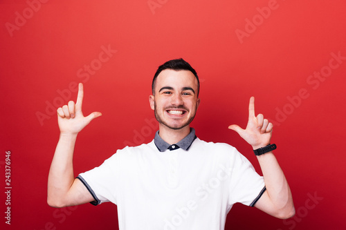 Handsome young boy in white tshrit pointing up  at copy space