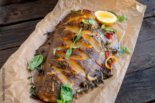 Valokuva baked flounder fish whole with seasonings, lemon and Basil on parchment