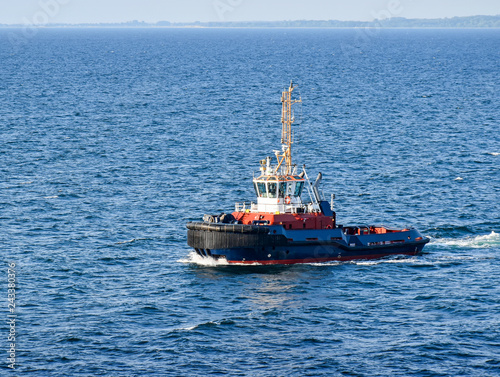A tugboat navigates on the sea, in the background the coast can be seen  © balipadma