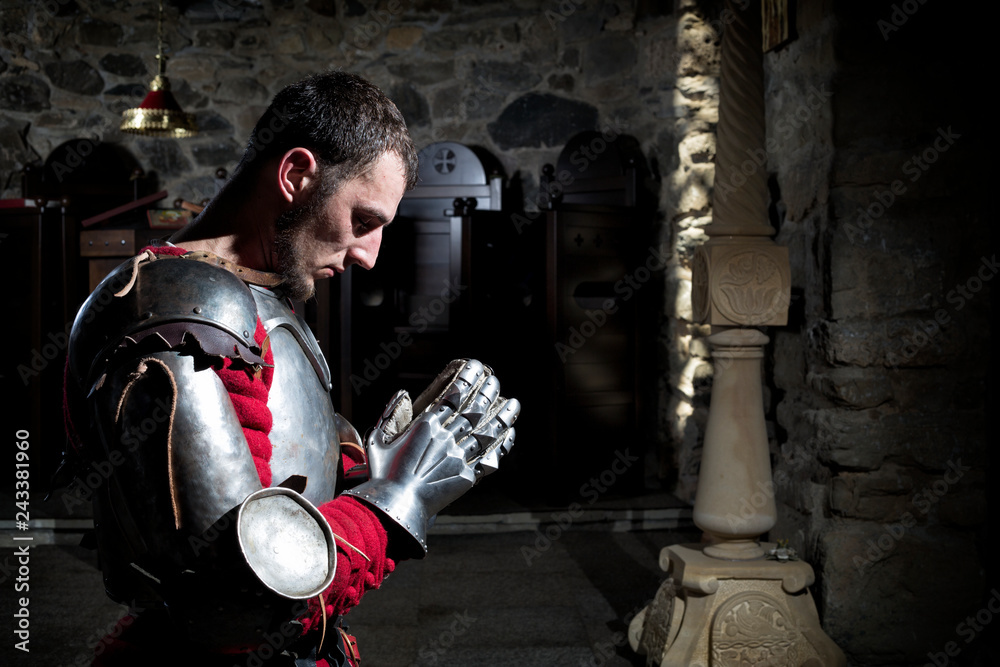 Side View Of Knight Kneeling On His Knees Praying Before Battle Stock