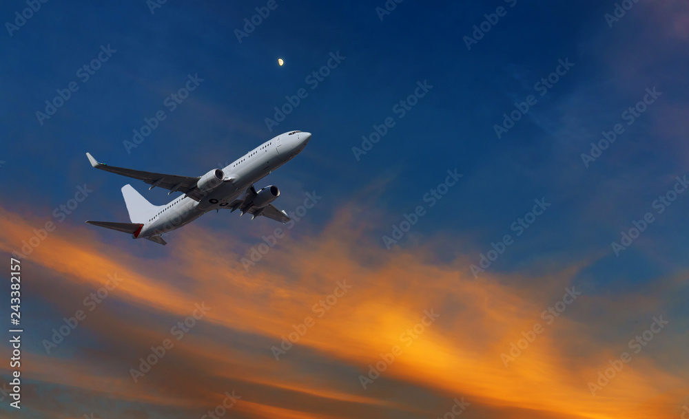 Commercial airplane climbing after take off in the sunset orange and yellow