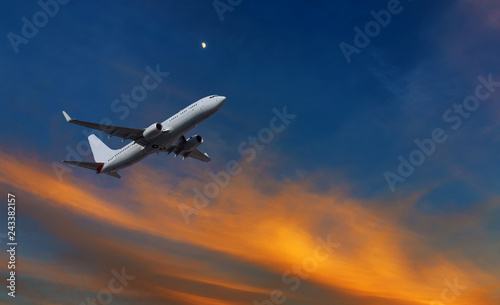 Commercial airplane climbing after take off in the sunset orange and yellow