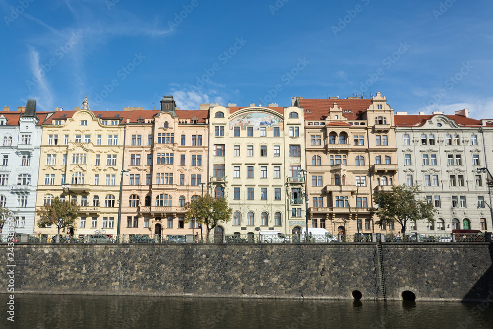 Row of old buildings on Vltava river waterfront,  in front of summer blue sky, in Prague, Czech Republic
