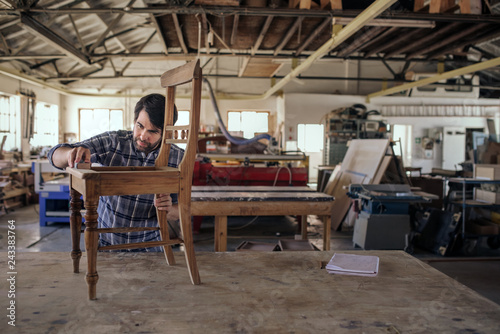 Woodworker sanding a chair on his workshop table
