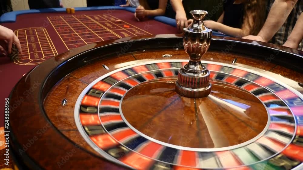 Closeup shot of casino roulette spinning around with casino chips put in piles near. Hands of urecognizable people holding cards and chips, people gambling. Casino concept. hd Closeup shot of casino roulette spinning around with casino chips put in piles near. Hands of urecognizable people holding cards and chips, people gambling. Casino concept. hd