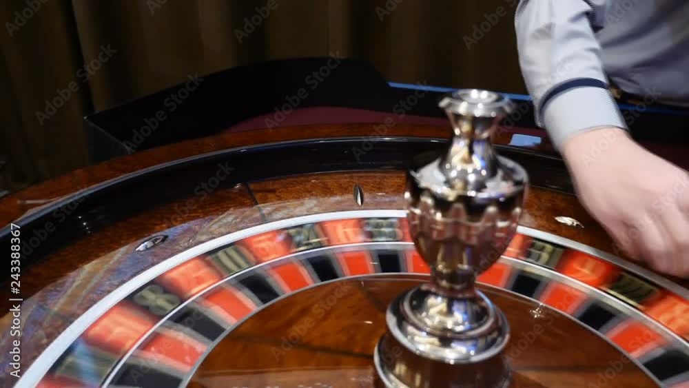 Casino theme. Top view on roulette in motion, white ball spinning. Bad luck and Good luck concept. Roulette wheel running. City nightlife entertainment. Dealer hand moves the roulette. hd