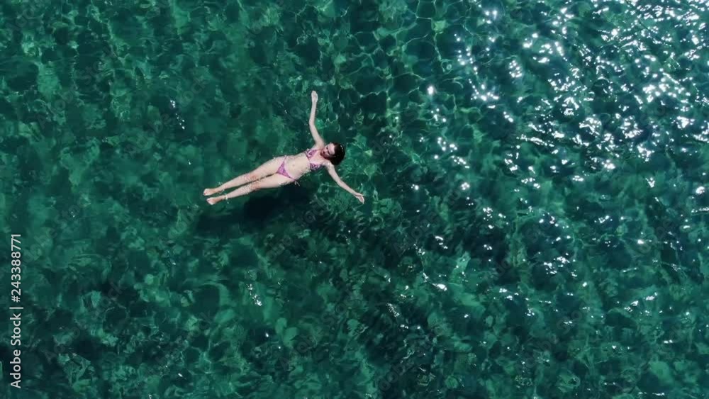 Aerial view on young woman floating on sea surface Aerial view on young woman floating on sea surface