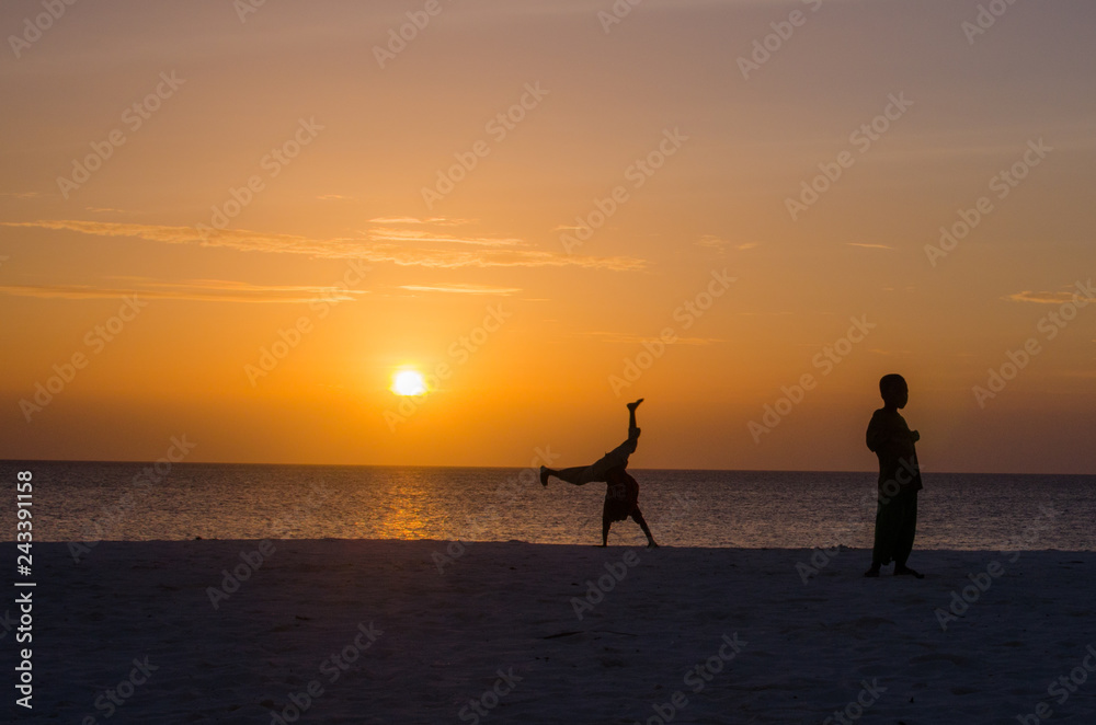 African kids playing on the sand in sunset beach