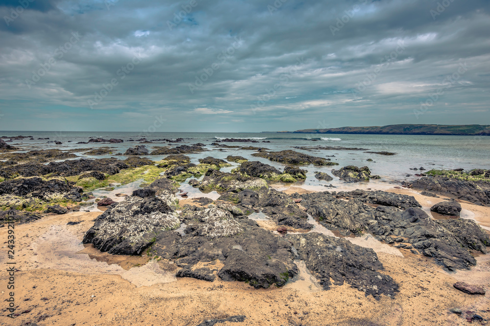 Dramatic landscape of Pembrokeshire coast, South Wales,Uk.Rocky beach during low tide and moody sky over horizon.Nature image with copy space.