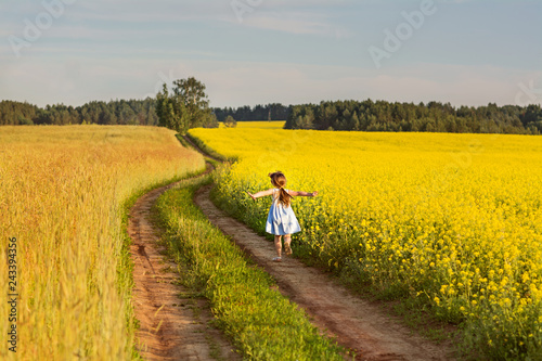 happy little girl running across the field of yellow flowers