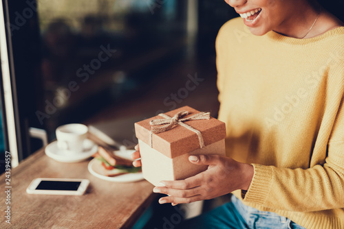 Young woman in sweater holding gift box in hands