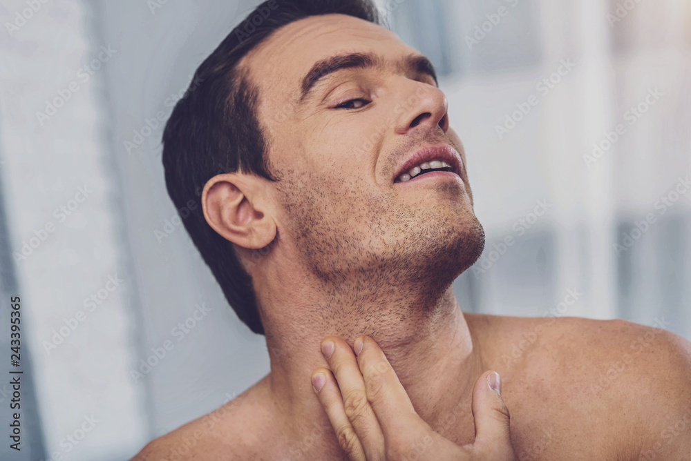 Obraz premium Positive handsome man applying a lotion