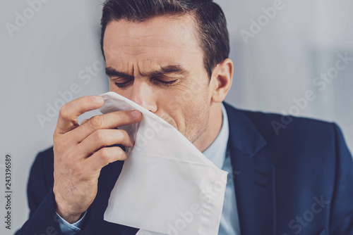 Unhappy young man sneezing