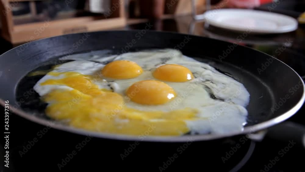 In the morning the girl prepares breakfast at home in the kitchen. Cooking eggs at home in the kitchen. Close-up In the morning the girl prepares breakfast at home in the kitchen. Cooking eggs at home in the kitchen. Close-up