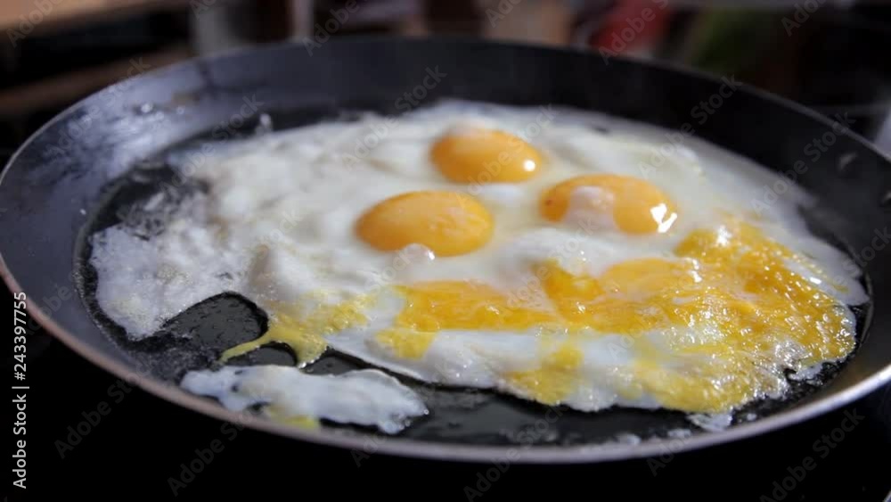 In the morning the girl prepares breakfast at home in the kitchen. Cooking eggs at home in the kitchen. Close-up In the morning the girl prepares breakfast at home in the kitchen. Cooking eggs at home in the kitchen. Close-up