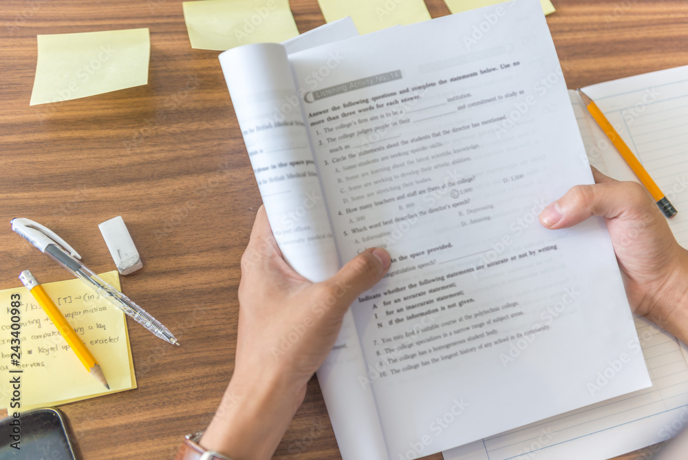 Obraz premium Rear view of student hands holding workbook and self studying