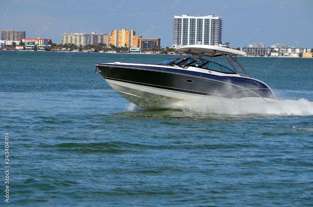 Obraz premium High-end motorboat with white fiber glass canopy on the Intra-Coastal Waterway with Miami building skyline in the background