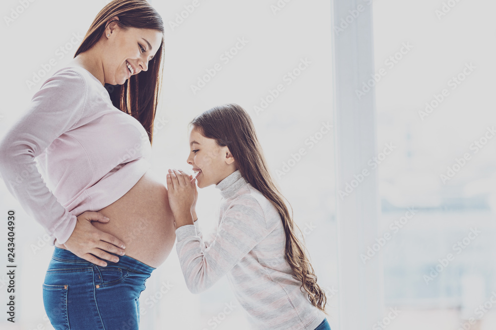 Cute little girl talking to her pregnant mothers belly