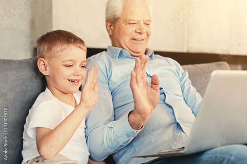 Cheerful grandfather and grandson making video call