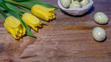 Happy easter copyspace featuring yellow tulips and eggs on wooden board
