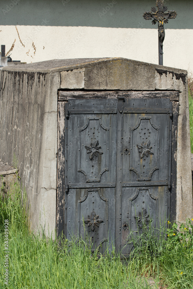Old locked heavy metal door at tomb entrance to burial crypt 