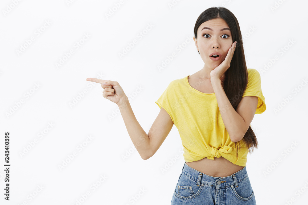 No make-up, beauty and emotions concept. Intrigued and surprised attractive asian female in cropped yellow t-shirt gasping opening mouth from shock touching cheek and pointing left curious, questioned No make-up, beauty and emotions concept. Intrigued and surprised attractive asian female in cropped yellow t-shirt gasping opening mouth from shock touching cheek and pointing left curious, questioned