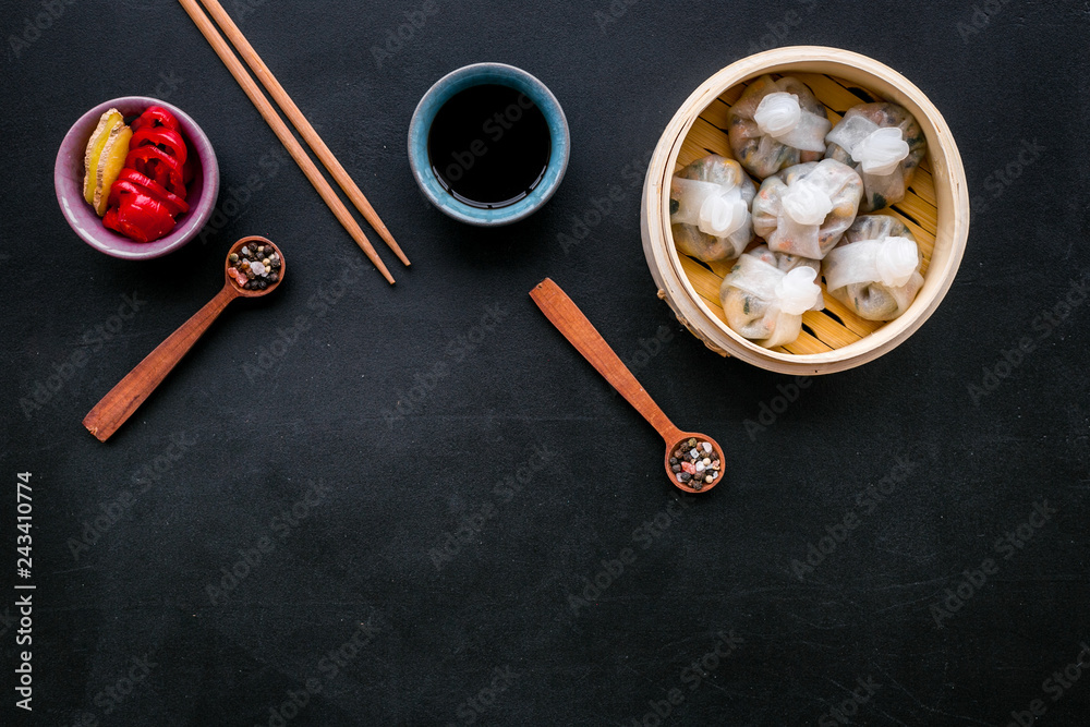 Chinese food set with dim sum, sticks and tea on black background top view copy space Chinese food set with dim sum, sticks and tea on black background top view copy space