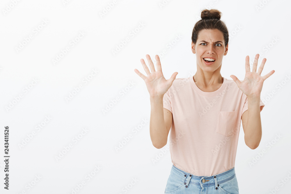 Displeased awkward and bothered young funny female with messy bun making grimace from aversion and dislike waving raised palm in refusal or rejection gesture as hearing disgusting suggestion Displeased awkward and bothered young funny female with messy bun making grimace from aversion and dislike waving raised palm in refusal or rejection gesture as hearing disgusting suggestion