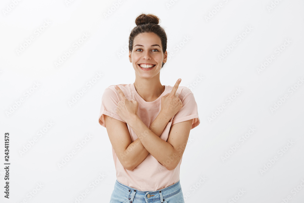 Obraz premium Optimistic good-looking friendly and young womanw ith tan and bright smile pointing sideways with arms crossed on body showing nice choices to try and buy grinning feeling confident and carefree