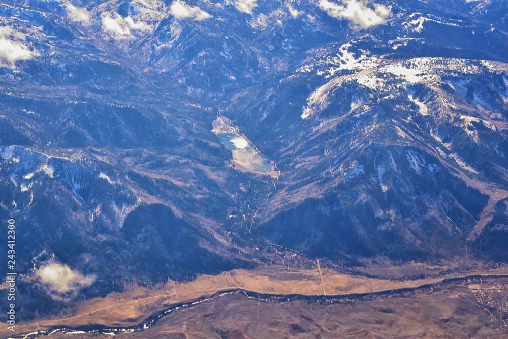 Aerial view of topographical Rocky Mountain landscapes on flight over Colorado and Utah during winter. Grand sweeping views of rivers, mountain and landscape patterns. Top view, Rockies and Wasatch Fr