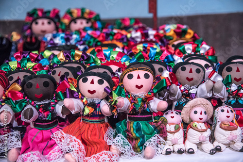 muñecas mexicanas tradicionales, vestidas con listones coloridos y tiernas caras en un fondo colorido
