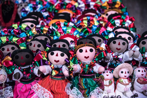 muñecas mexicanas tradicionales, vestidas con listones coloridos y tiernas caras en un fondo colorido