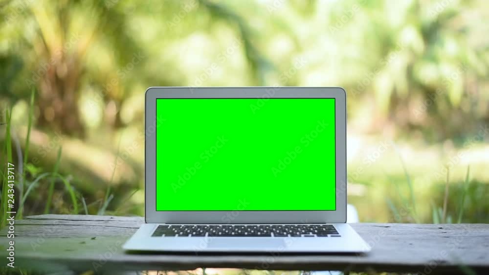 A laptop computer with a key green screen set on work office table. A laptop computer with a key green screen set on work office table.